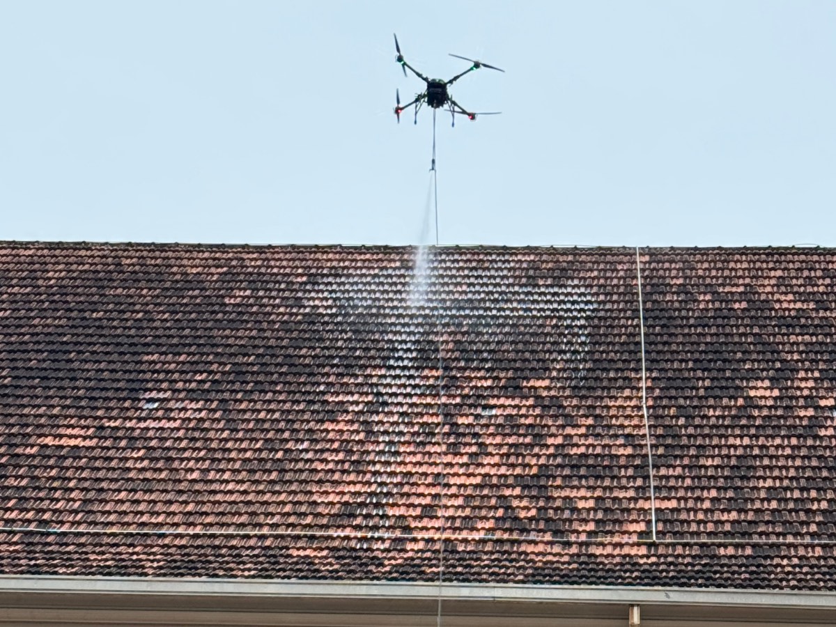 Drone lavando com jato de água o telhado de telhas cerâmicas de uma igreja